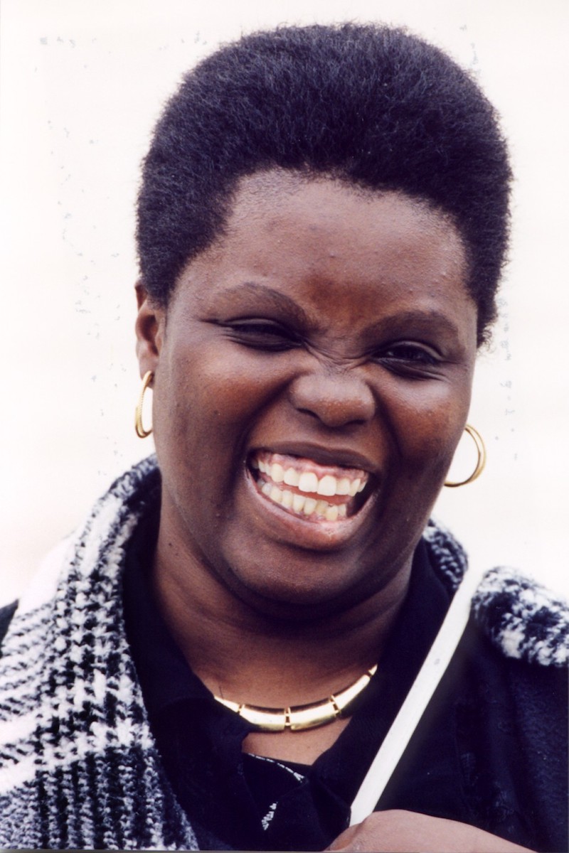 Lois Curtis, a black woman wearing a multicolored scarf, smiling joyously.